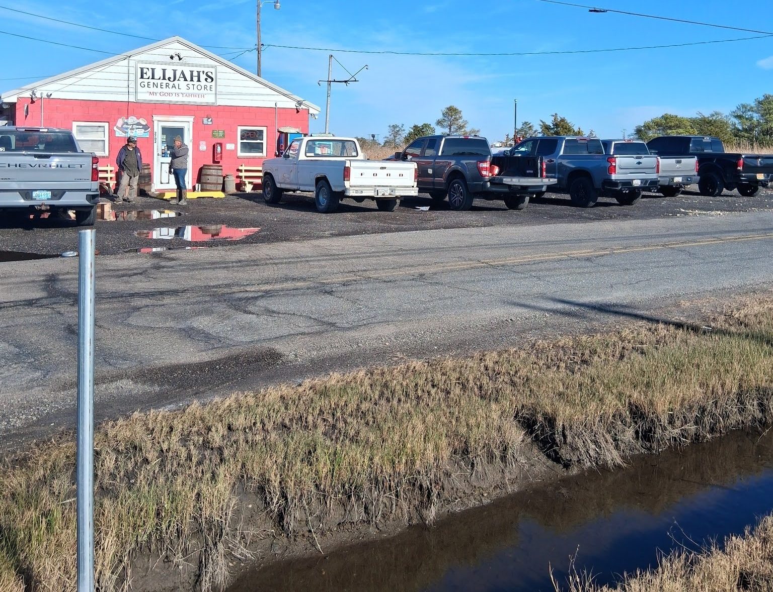 A small convenience store, painted red and white, with a parking lot full of trucks.