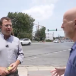 A screencap of the video, featuring Tim and Bernard sweating in the heat alongside a street