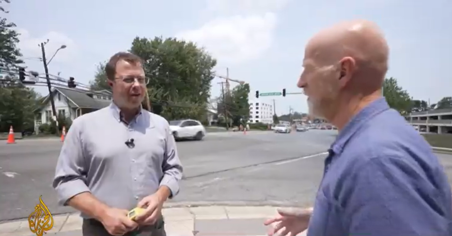 A screencap of the video, featuring Tim and Bernard sweating in the heat alongside a street
