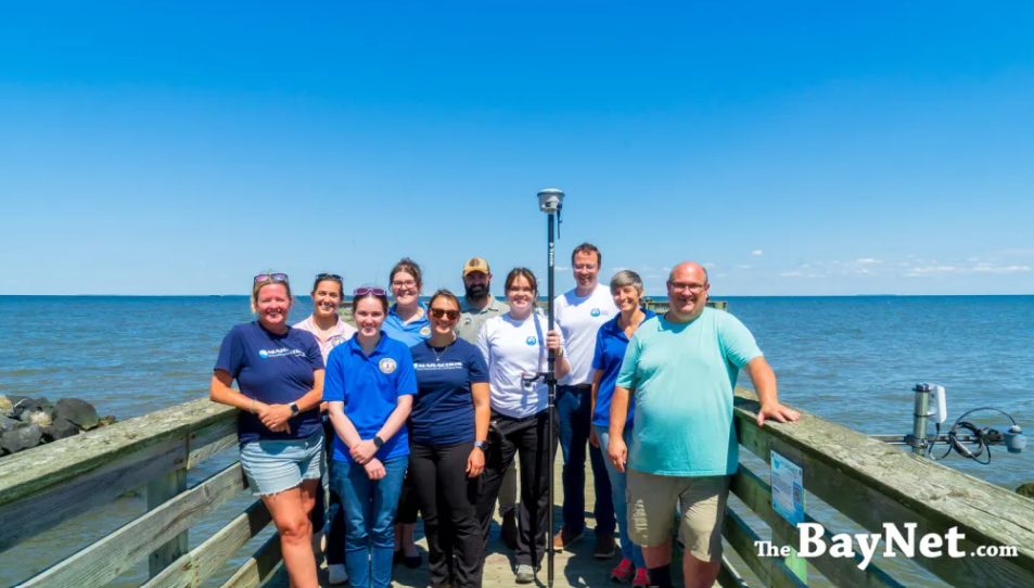 A group of people stand on a dock, posing with the new HydroNet water sensor